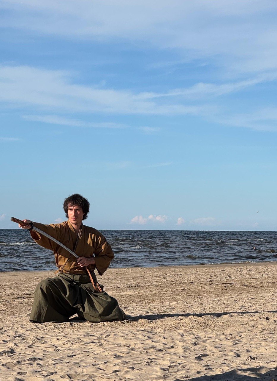 Mansur Kohaku kneeling on the beach with the katana drawn